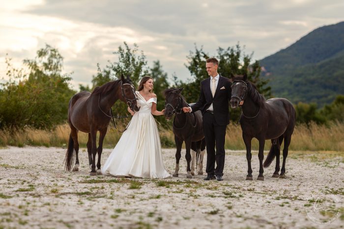 Novomanželé se líbají v sedle koní na lesní cestě