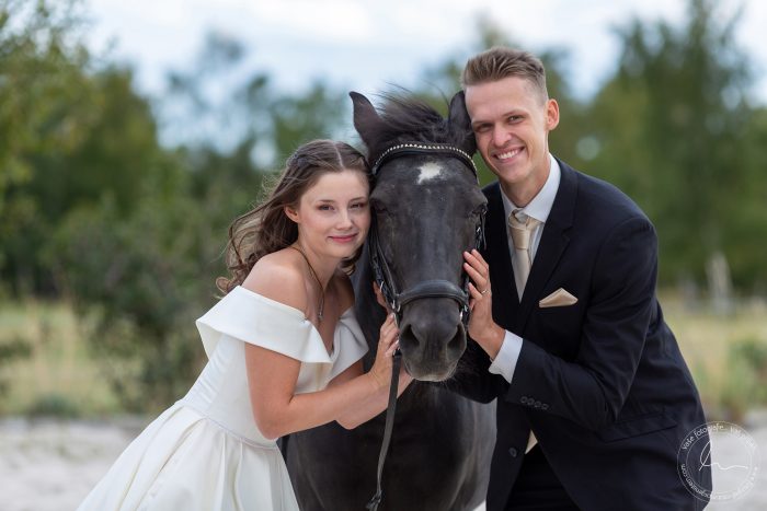 Novomanželé se líbají v sedle koní na lesní cestě
